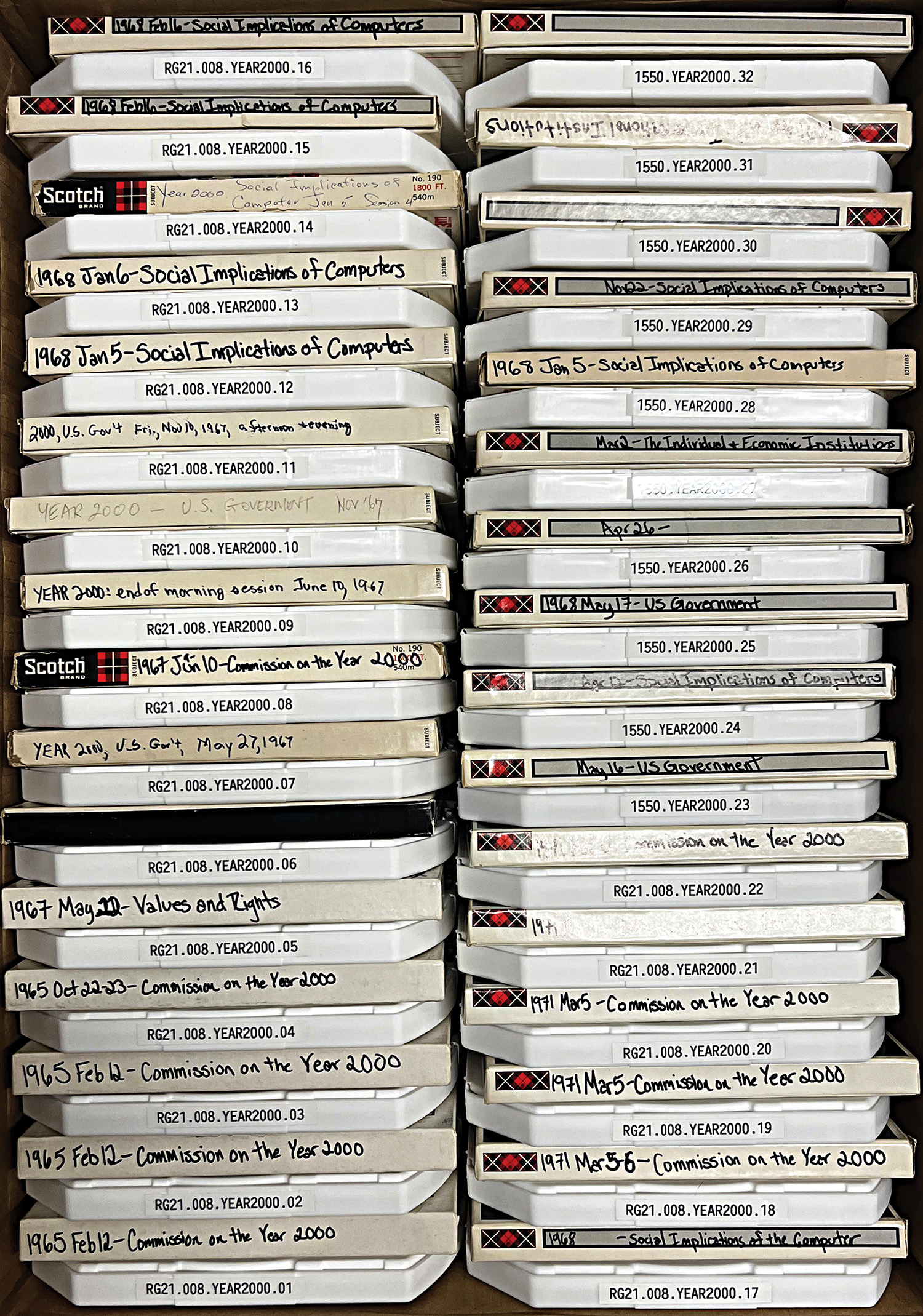 Two columns of audiotapes boxed in white cases with labels showing sequenced alphanumeric codes and the category “YEAR 2000.”