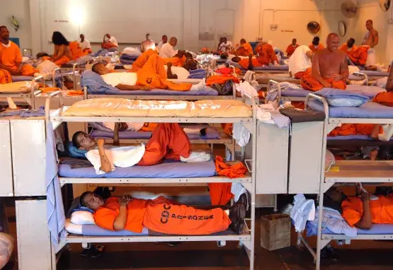 Prisoners sleeping in triple bunk beds stuffed into large room