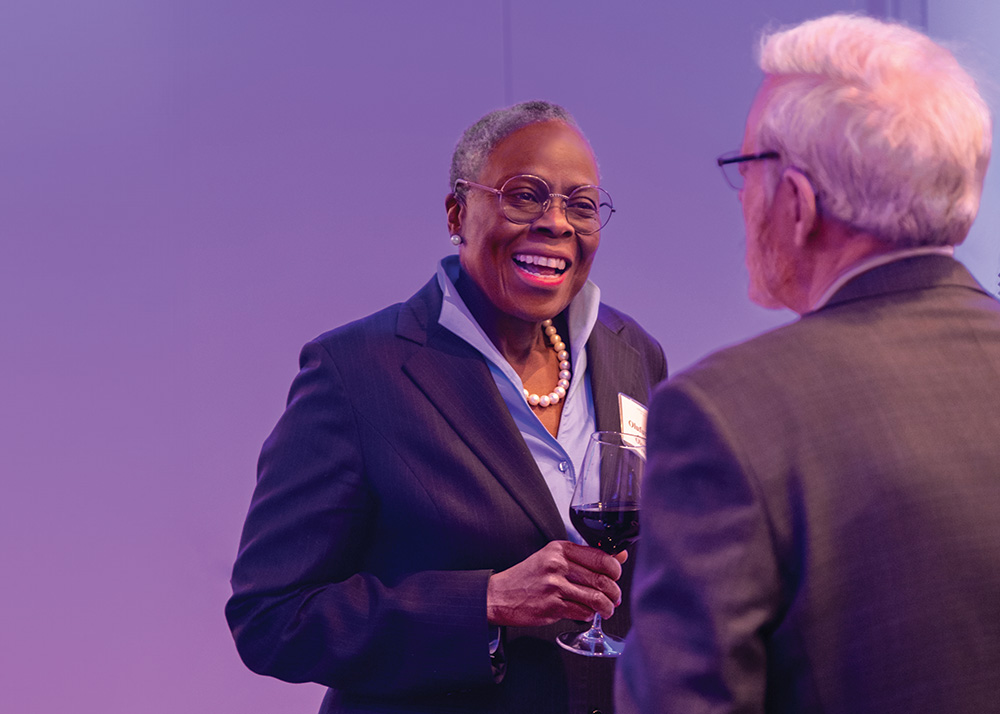 A woman in a suit smiles while in conversation. 