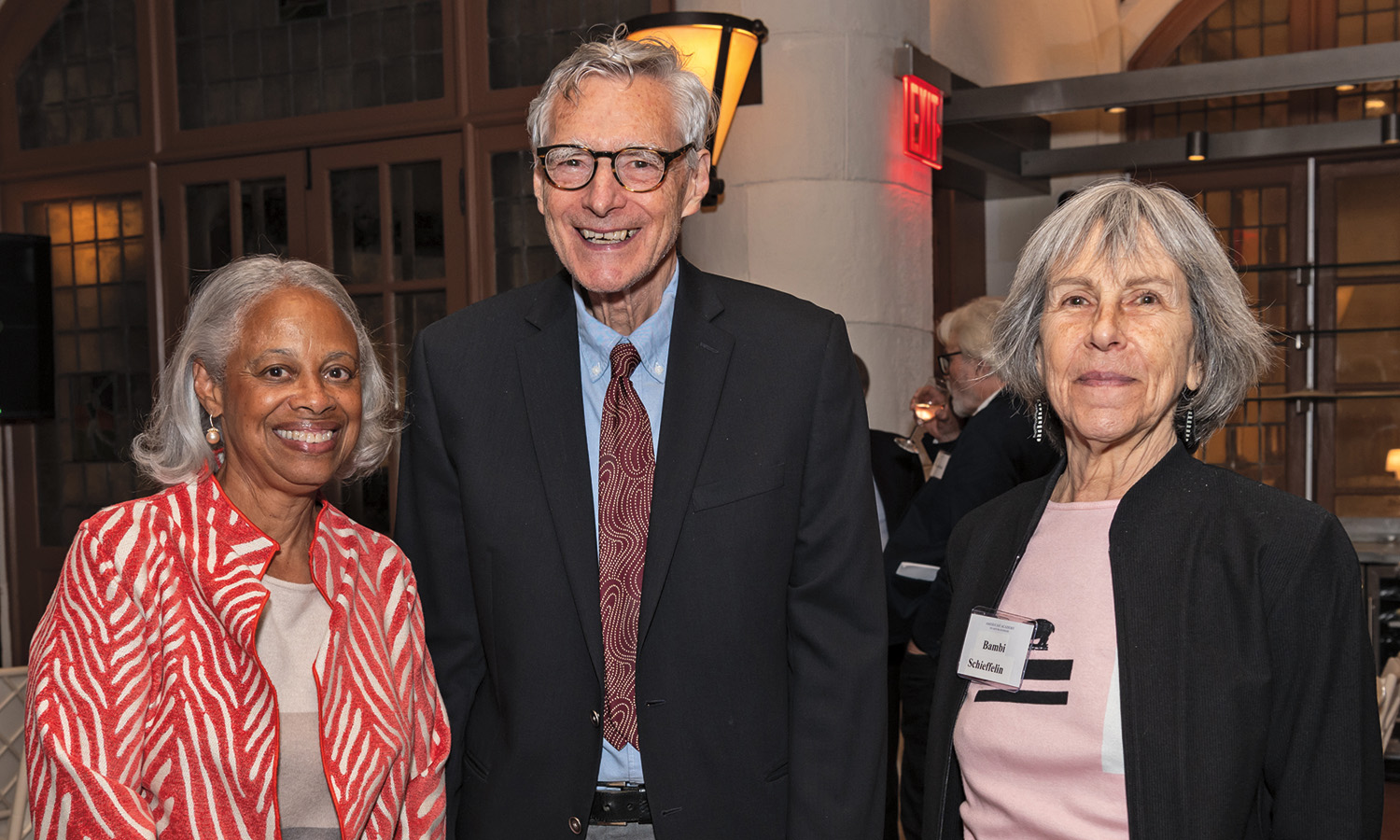 Three formally dressed people pose for a photo at an evening reception. 