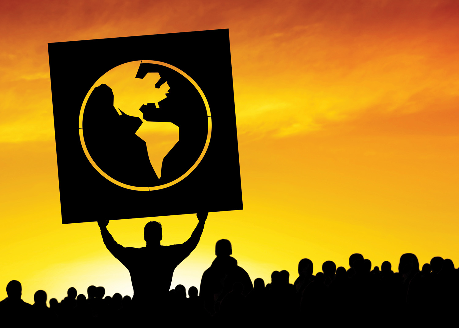 A silhouette of people with one individual holding up a sign that shows the Western Hemisphere.