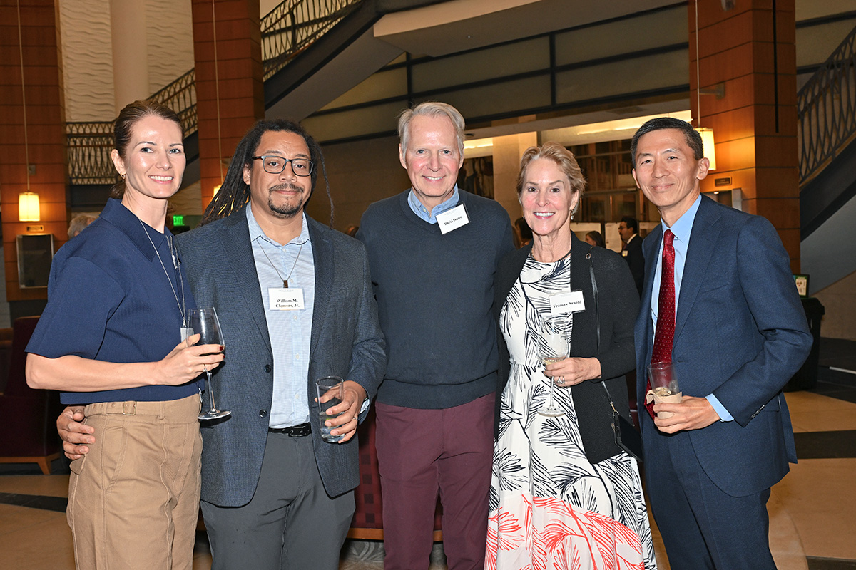 People in business attire smile and pose at a cocktail reception.