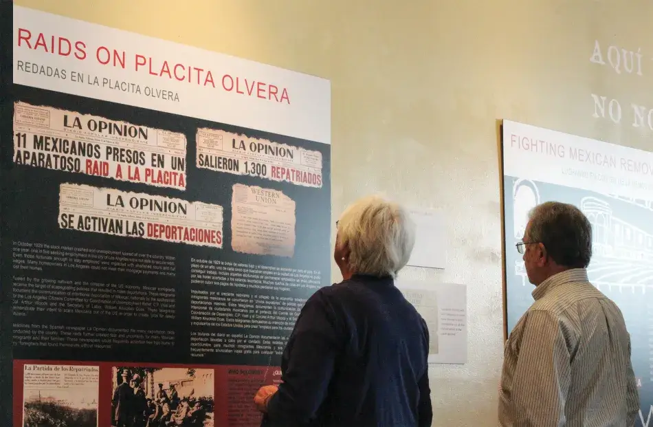 Two visitors examine the Boyle Heights Museum exhibition Aquí Estamos Y No Nos Vamos at CASA 0101 in East Los Angeles, 2017