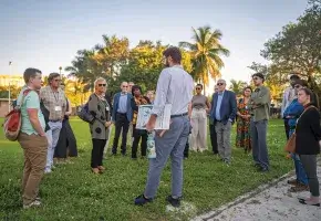 Members of the Commission on Accelerating Climate Action stand in a grassy park in Miami’s Little River neighborhood while on a walking tour led by staff at the Miami-Dade County Office of Resilience.