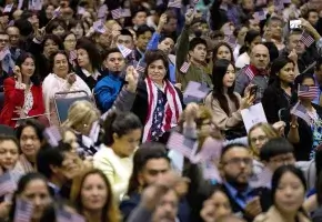 People wave U.S. flags during a 2017 naturalization ceremony at the Los Angeles Convention Center.